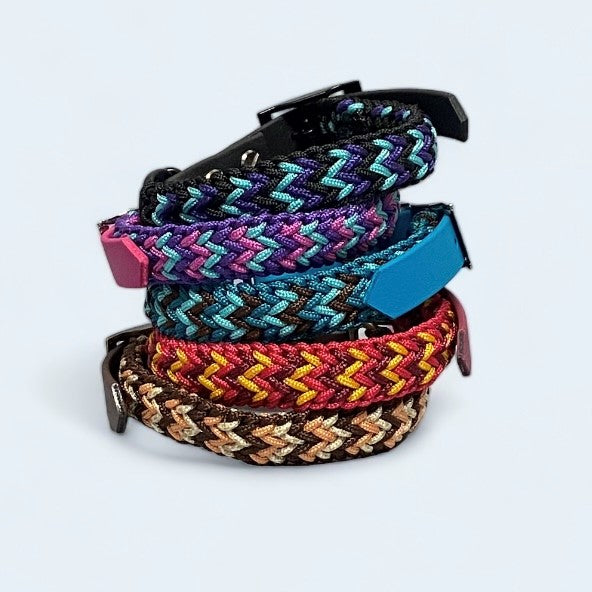Selection of brightly coloured small dog collars stacked on top of each other on a light background.